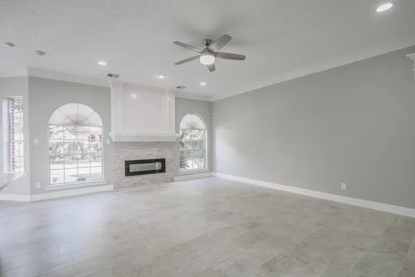 an empty room with windows and fireplace
