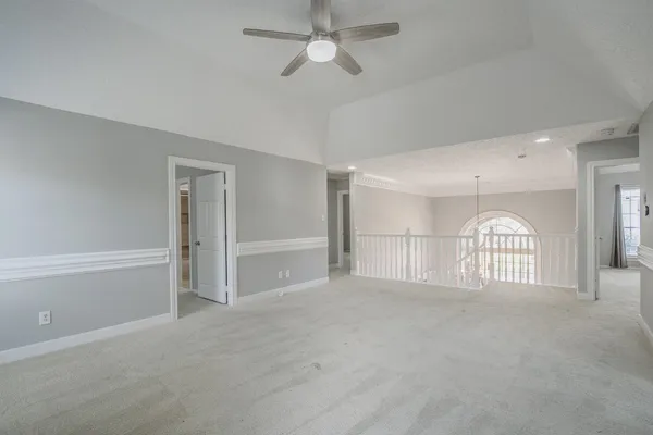 a view of a livingroom with a chandelier a ceiling fan and windows