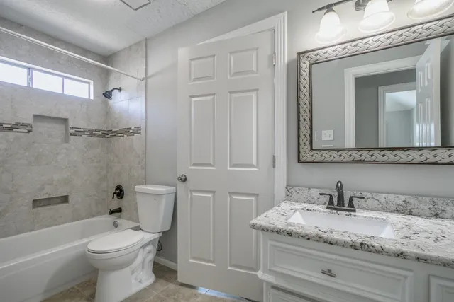 a bathroom with a granite countertop toilet a sink and bathtub