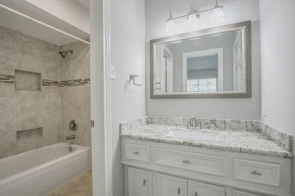 a bathroom with a granite countertop bathtub shower sink vanity and mirror