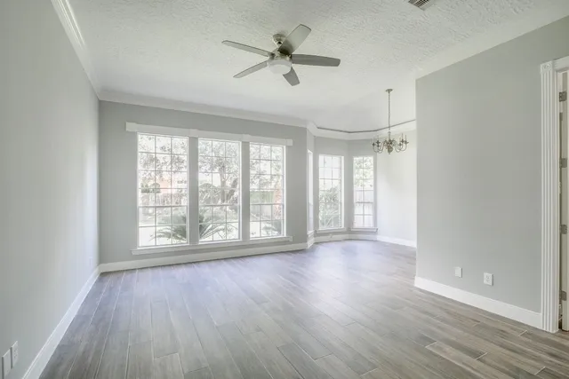 a view of an empty room with a window and wooden floor