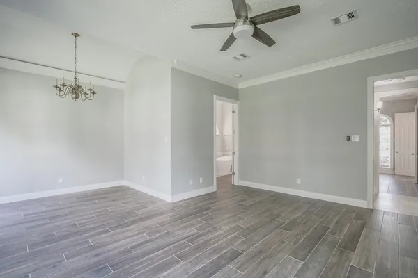 an empty room with wooden floor fan and windows