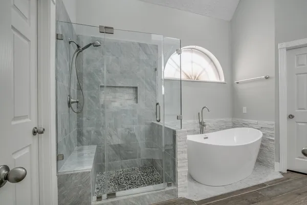 a bathroom with a white bath tub a mirror and a shower