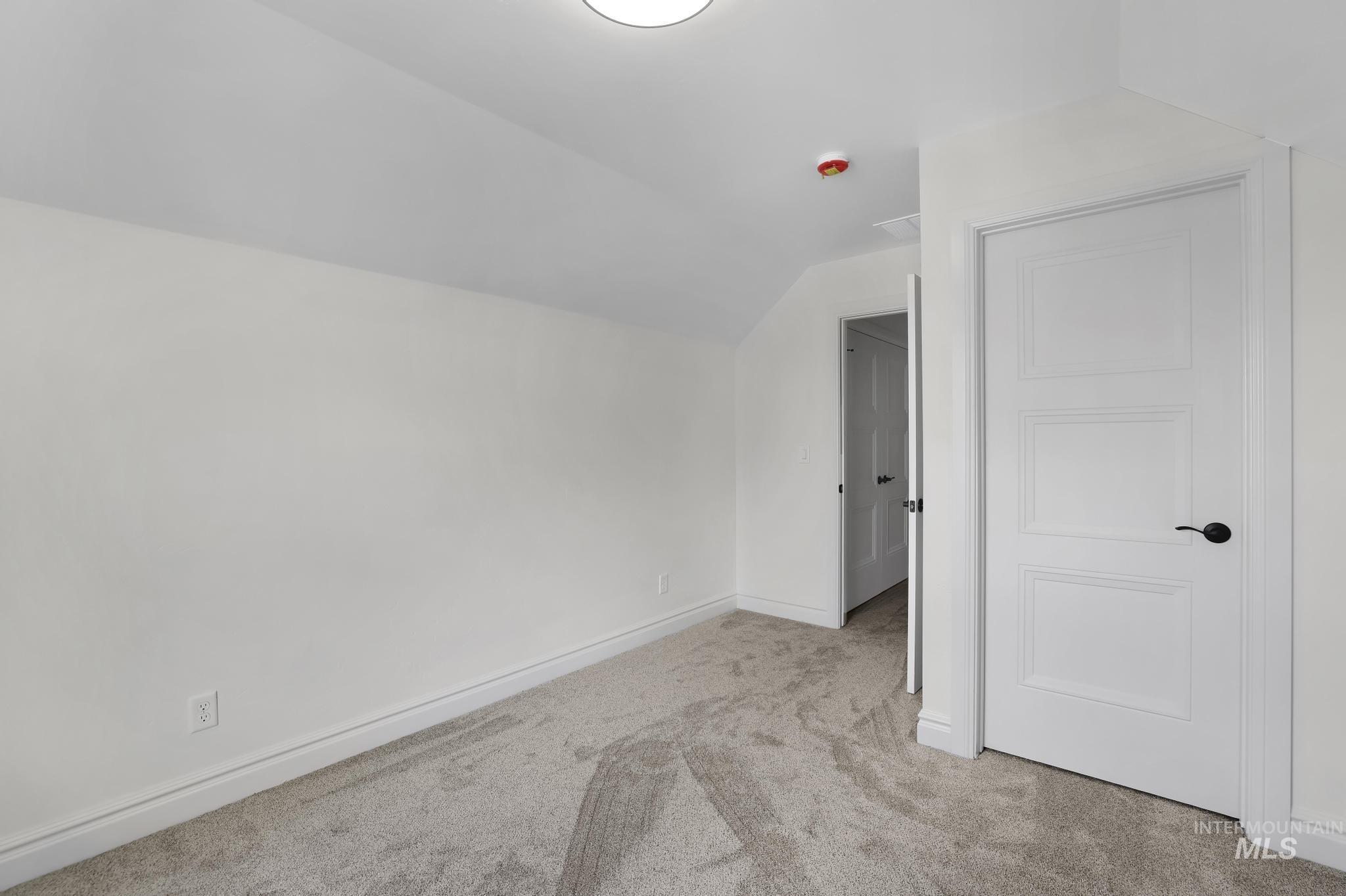 866 Quartz Road Kimberly, ID 83341 - Photo 45 of 48 Attic room featuring neutral carpeting, white baseboards, and a contemporary white door with black hardware