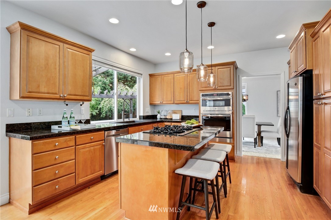 17264 Southeast 185th Street Renton, WA 98058 - Photo 6 of 40 a kitchen with stainless steel appliances granite countertop a stove a refrigerator a kitchen island a stove and a wooden floors
