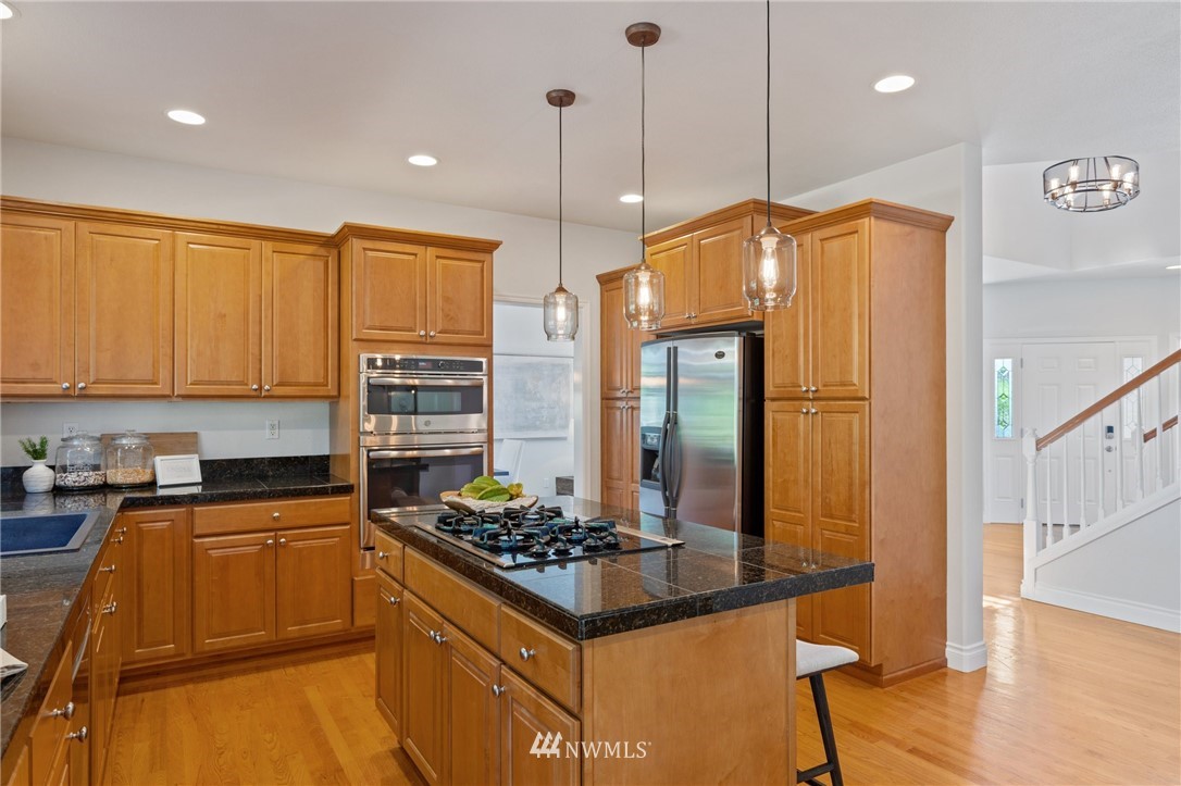 17264 Southeast 185th Street Renton, WA 98058 - Photo 9 of 40 a kitchen with stainless steel appliances granite countertop a stove a sink dishwasher and a refrigerator with wooden floor