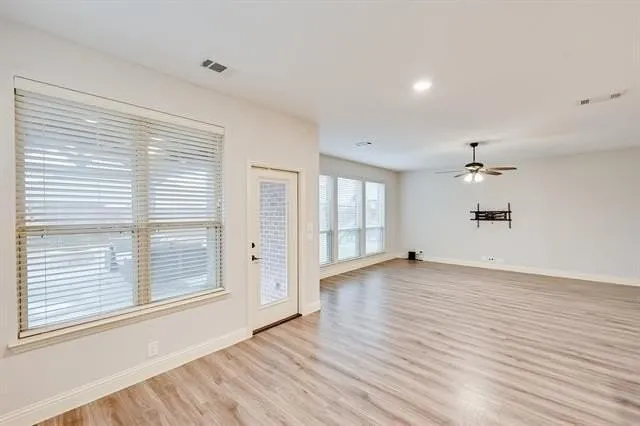 a view of an empty room with a window and wooden floor