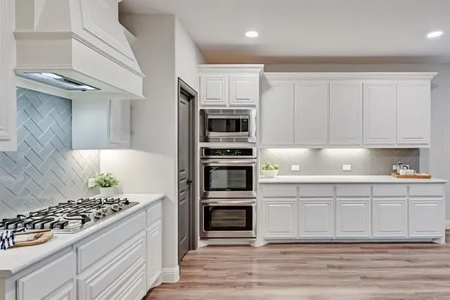 a kitchen with kitchen island white cabinets and stainless steel appliances