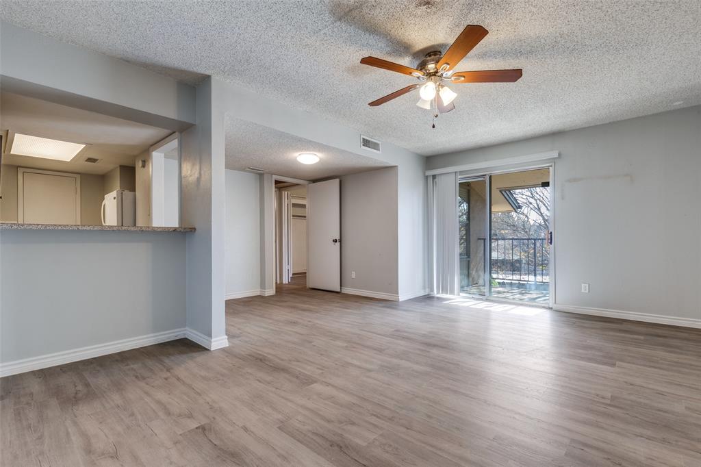 a view of an empty room with wooden floor and a ceiling fan