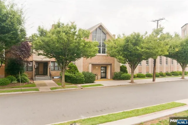 a front view of a house with a garden and trees