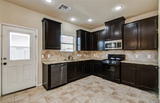 a kitchen with stainless steel appliances granite countertop a sink stove and refrigerator