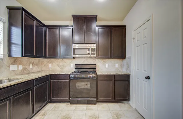 a kitchen with granite countertop a sink and a stove