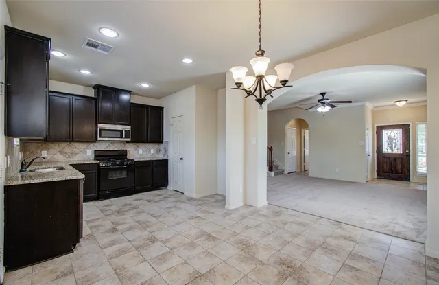a view of an empty room with a chandelier fan