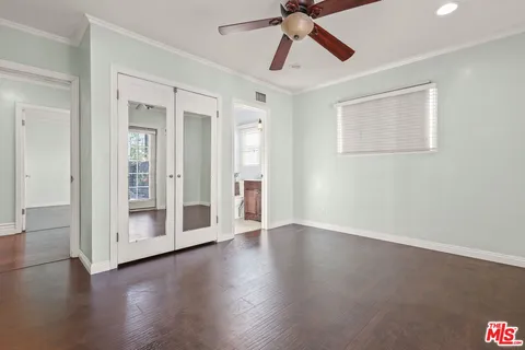 a view of an empty room with wooden floor and a ceiling fan
