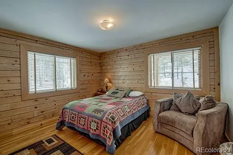 a bedroom with a bed couch and windows