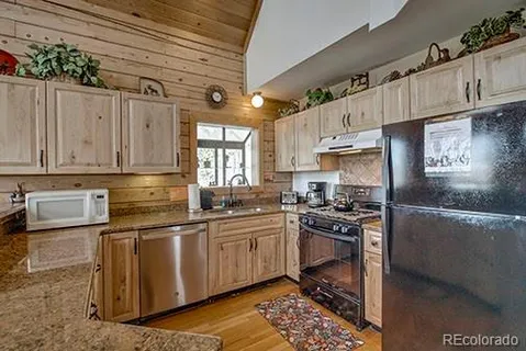 a kitchen with stainless steel appliances a sink a stove a refrigerator cabinets and a dining table