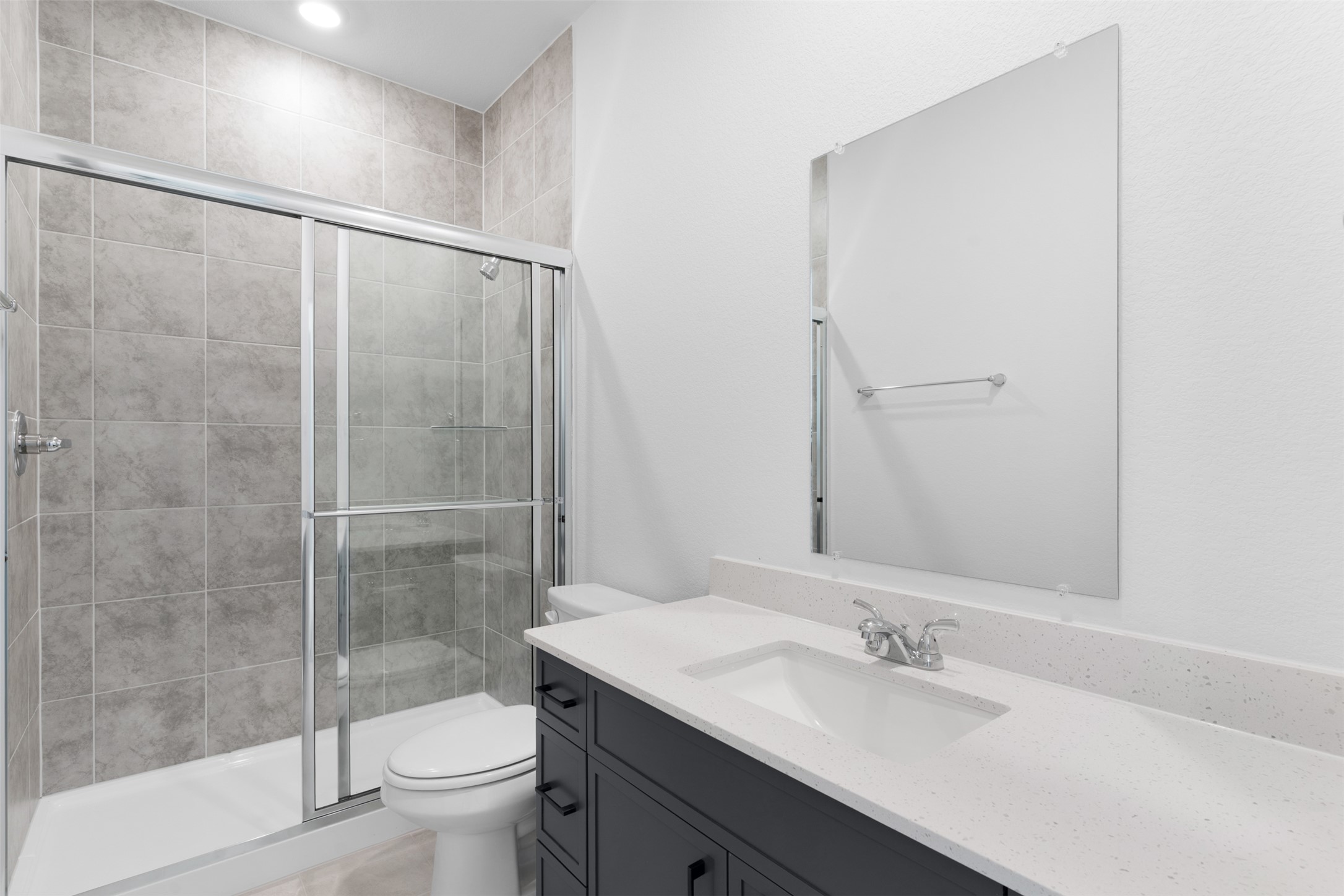 316 Ridgewell Loop Georgetown, TX 78633 - Photo 16 of 25 Bathroom featuring a shower with sliding glass doors, light-toned tiled walls, a dark vanity with a light-colored countertop, and a rectangular mirror