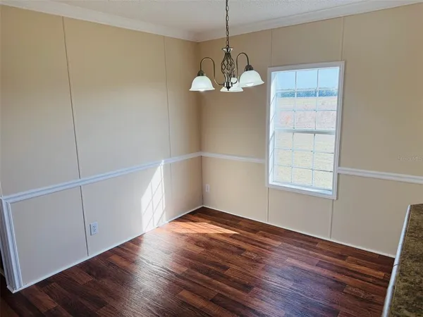 an empty room with wooden floor cabinet and windows