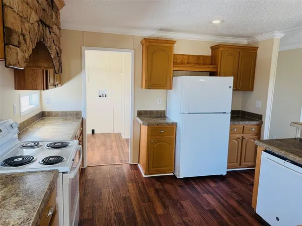 a kitchen with a refrigerator a stove top oven a counter space and wooden floor