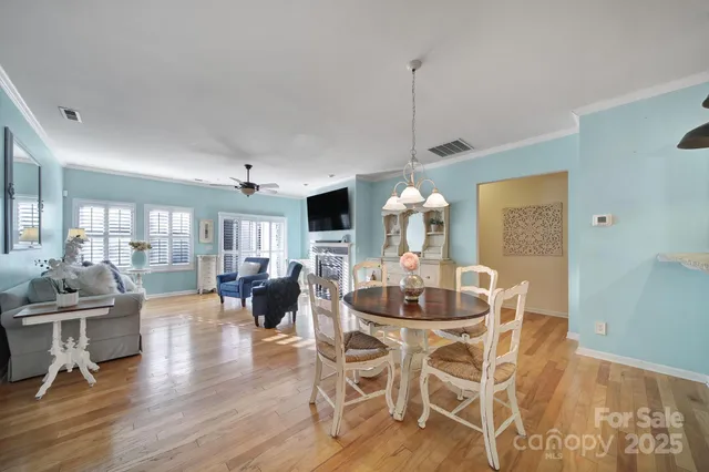 a dining room with wooden floor a chandelier a wooden table and chairs