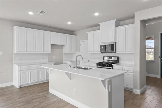 a kitchen with white cabinets a sink stove and refrigerator