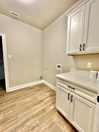 a view of a kitchen with white cabinets and wooden floor