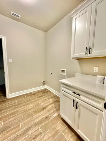 a view of a kitchen with white cabinets and wooden floor
