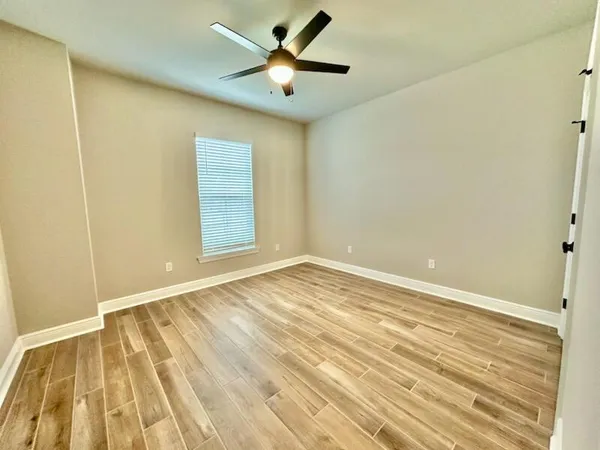 a view of a room with wooden floor and a ceiling fan