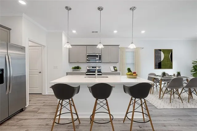 a kitchen with stainless steel appliances granite countertop a refrigerator a stove a kitchen island a dining table and chairs with wooden floor