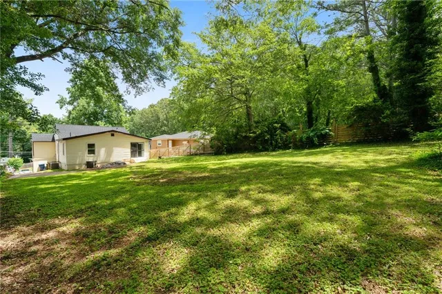 a white house in a big yard with large trees
