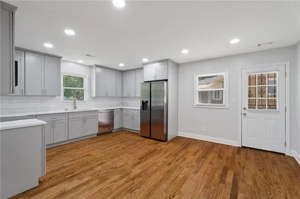 a large kitchen with a refrigerator a sink dishwasher and a stove with wooden floor