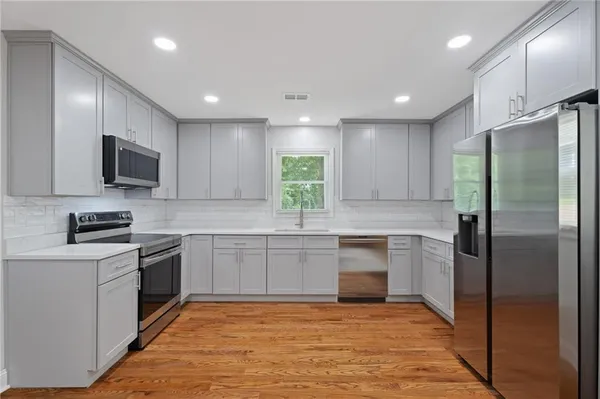 a kitchen with kitchen island granite countertop stainless steel appliances cabinets a sink and a window