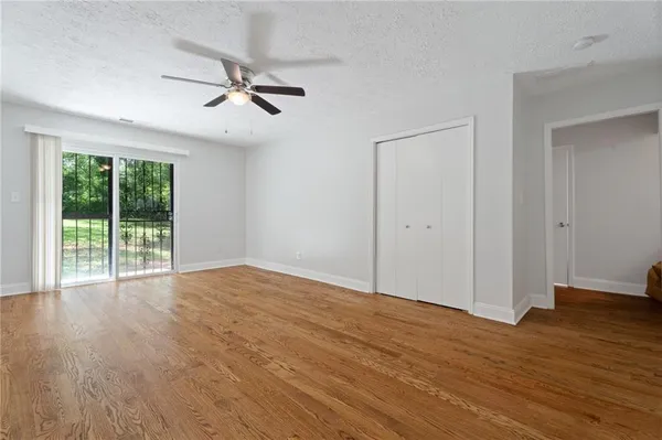 a view of an empty room with wooden floor and a window