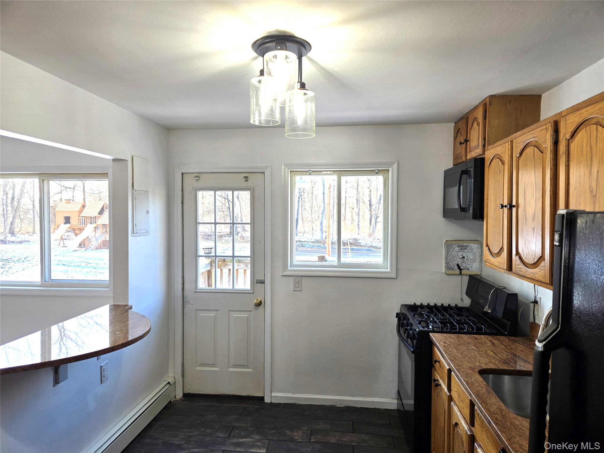 9 Fishkill Glen Drive, Unit F Fishkill, NY 12524 - Photo 5 of 10 Kitchen with brown cabinets, black appliances, a baseboard radiator, and hanging light fixtures