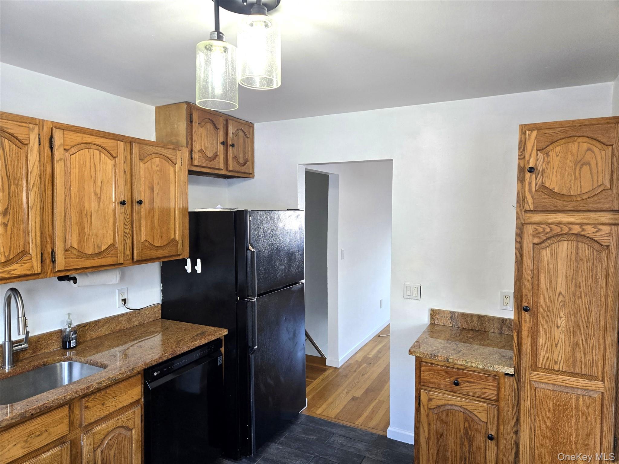 9 Fishkill Glen Drive, Unit F Fishkill, NY 12524 - Photo 6 of 10 Kitchen featuring brown cabinets, dark stone countertops, black dishwasher, and dark wood-type flooring