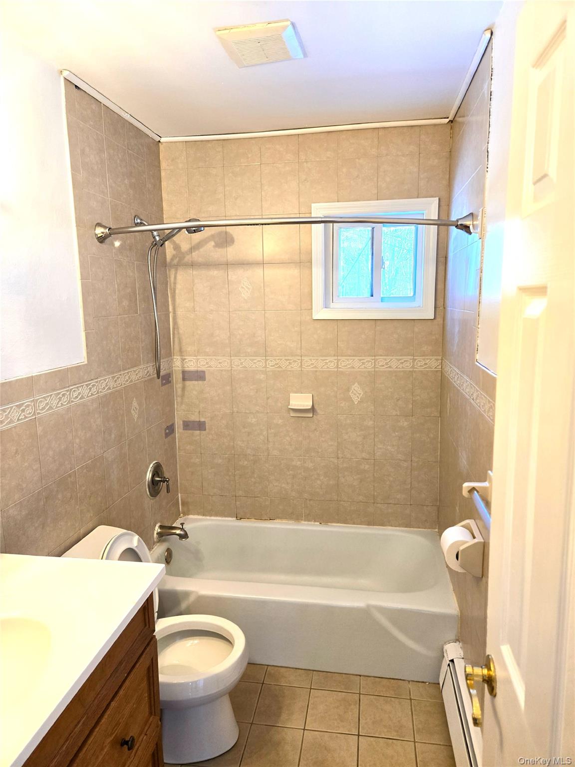 9 Fishkill Glen Drive, Unit F Fishkill, NY 12524 - Photo 9 of 10 Full bath featuring tile walls, shower / washtub combination, vanity, light tile patterned flooring, and a baseboard heating unit