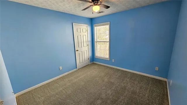 an empty room with windows and a chandelier fan