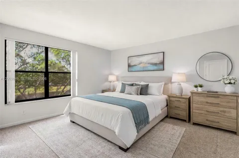 a spacious bedroom with a bed a mirror and a large window