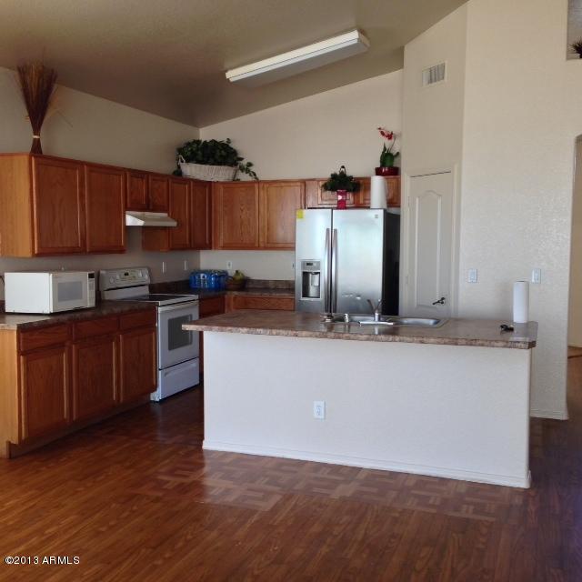 3228 West Maldonado Road Phoenix, AZ 85041 - Photo 2 of 6 a kitchen with kitchen island granite countertop wooden floors and white stainless steel appliances