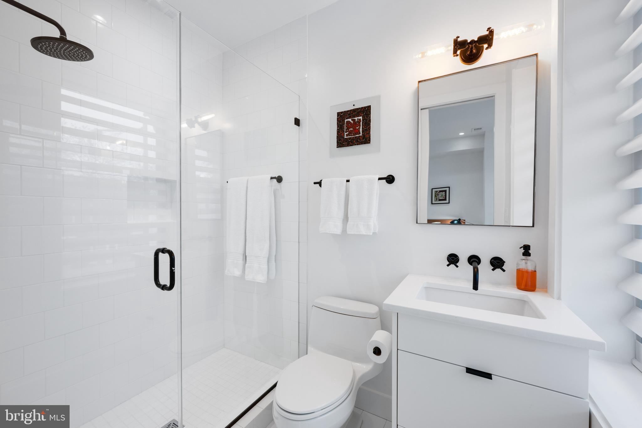 1806 9th Street Northwest, Unit 2 Washington, DC 20001 - Photo 14 of 40 a bathroom with a sink a mirror a vanity and shower