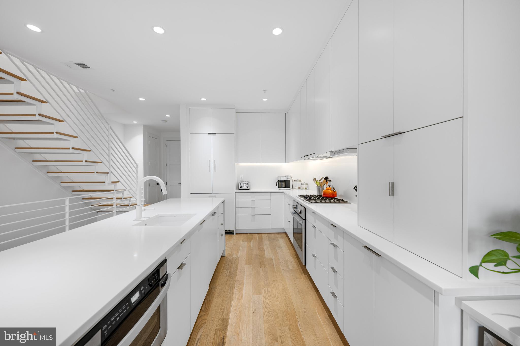 1806 9th Street Northwest, Unit 2 Washington, DC 20001 - Photo 4 of 40 a large white kitchen with wooden floor and a sink