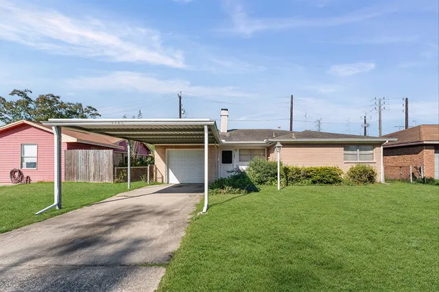a view of a house next to a big yard with plants and large trees