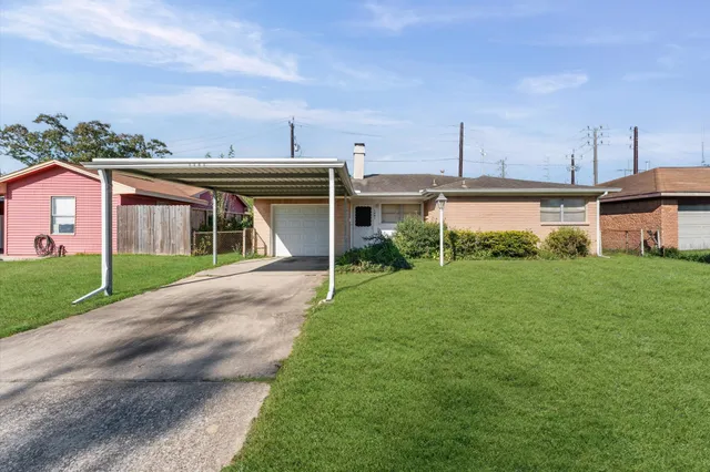 a view of a house next to a big yard with plants and large trees