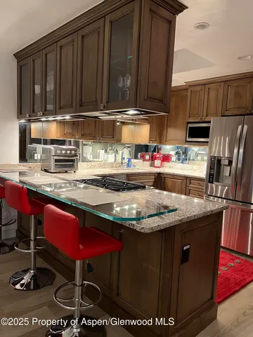 a kitchen with kitchen island granite countertop a stove a microwave a sink and cabinets