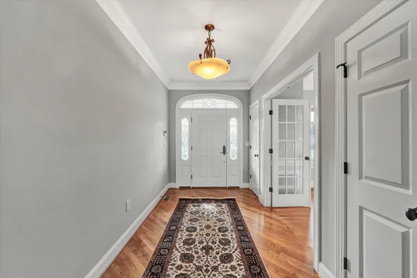 a view of a hallway with wooden floor and a chandelier