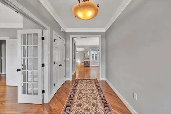 a view of a hallway with wooden floor and a bathroom