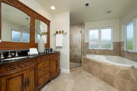 a bathroom with a granite countertop tub sink a mirror and a bathtub