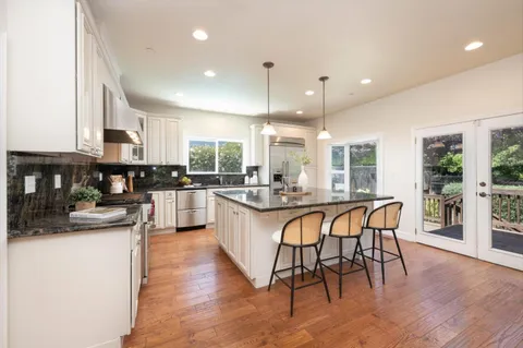 a kitchen with stainless steel appliances granite countertop wooden floor window dining table and chairs