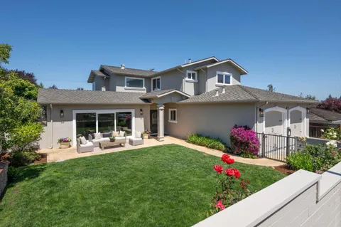 a front view of a house with a yard and potted plants