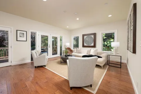 a living room with furniture floor to ceiling window and wooden floor
